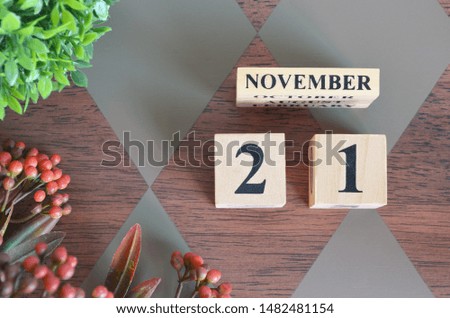 November 21. Date of November month. Number Cube with a flower and leaves on Diamond wood table for the background