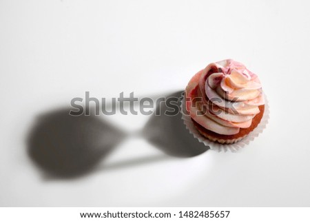 Conceptual image of cup cake with shadow of hourglass. Isolated stock photo