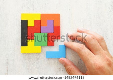 business concept image of a colorful square tangram puzzle, over wooden table