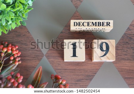 December 19. Date of December month. Number Cube with a flower and leaves on Diamond wood table for the background