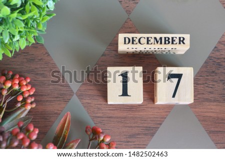 December 17. Date of December month. Number Cube with a flower and leaves on Diamond wood table for the background
