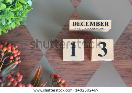 December 13. Date of December month. Number Cube with a flower and leaves on Diamond wood table for the background