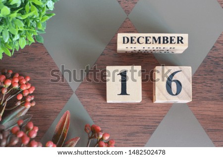 December 16. Date of December month. Number Cube with a flower and leaves on Diamond wood table for the background