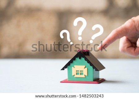 House Model with question marks over the desk and free copy space for your text. Man chooses a house.