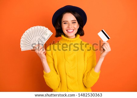 Photo of cheerful trendy excited nice girl proud to have earned considerable amount of money while isolated with orange background