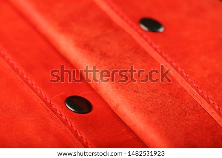 A pair of red genuine leather wallets with rivets on a dark background top view. Genuine leather