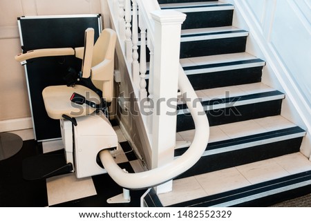 White stairlift on staircase for disabled people and elderly people indoor in home or school and office for free service. Royalty-Free Stock Photo #1482552329