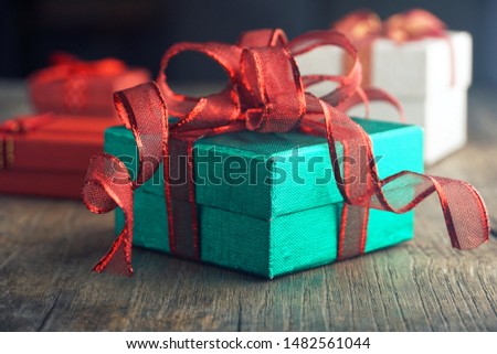 Green gift box with red ribbon for party on the the table.