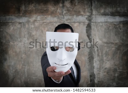 Businessman holding white mask in his hand dishonest cheating agreement.Faking and betray business partnership concept Royalty-Free Stock Photo #1482594533