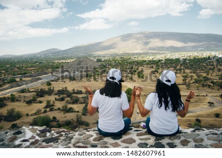 Rear view of a group of friends sitting together on a mountain and looking at pyrimids in Mexico
