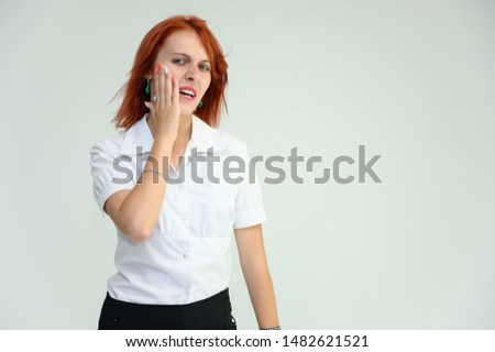 Photo Portrait of a cute girl woman with bright red hair manager in a white shirt on a white background in studio. He talks, shows his hands in front of the camera with emotions.