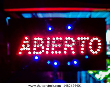 Urban night scene with open neon sign with spanish text "open"