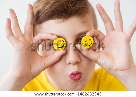 Laughing boy holding in his hand a funny yellow smileys instead of eyes