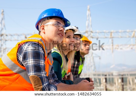 Group of young workers looking ahead in electric power station Royalty-Free Stock Photo #1482634055