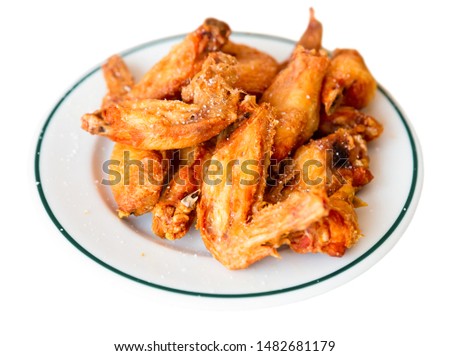 Picture of dish of tasty fried chicken wings served at plate. Isolated over white background
