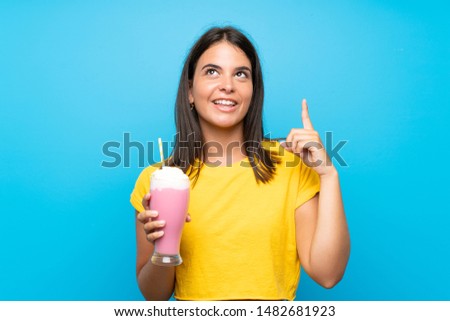 Young girl with strawberry milkshake over isolated background intending to realizes the solution while lifting a finger up