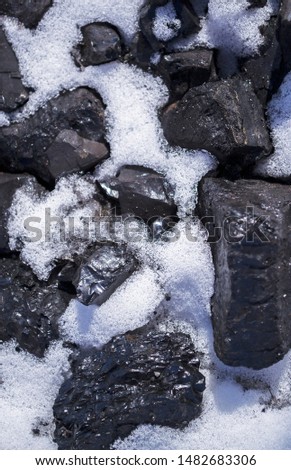 Pile of black coal covered with white snow. Winter heating. Energy supply security. Closeup. Selective focus Royalty-Free Stock Photo #1482683306