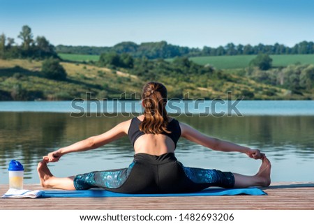 Girl doing stretching while sitting on a twine in full length against a background of beautiful nature