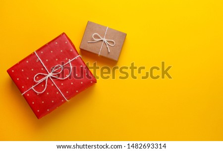 Two gifts wrapped in craft paper on a yellow background. Copy space.View from above, flat lay design,minimalism.Holiday gift concept.