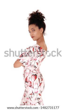 A gorgeous young multi-racial woman standing in a summer dress
in profile, with her arms crossed, with her black
curly hair in a bun, isolated for white background
