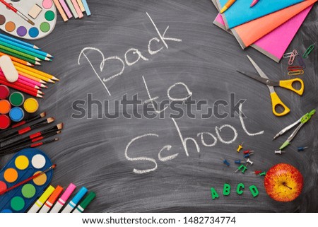 Stationery accessories on background of school blackboard with inscription: Back to school. Top view. School accessories for children's education and development.  Office supplies.