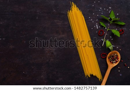 Ingredients for italian pasta spaghetti, basil leaves, tomatoes, on dark vintage background with space for text.