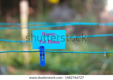 Blue clothes peg with blue note written " Honey I'm Home". Selective focus
