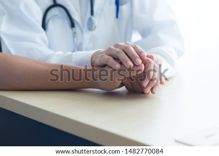 Two people holding hands for comfort. Doctor consoling relatives of patients. Vintage tone.