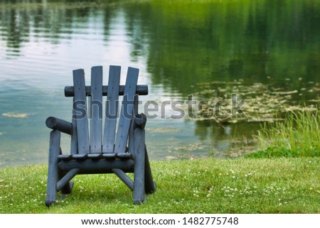 Black adirondack chair by a lake on a vacation by the lake up north. Royalty-Free Stock Photo #1482775748
