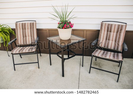 outdoor patio with two chairs and a small table and a plant