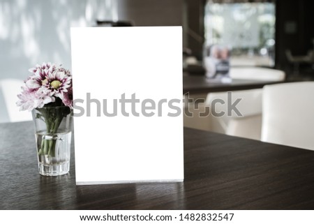 Mock up white Label for blank menu frame in restaurant cafe with plant flower. Stand booklet sheets paper tent card on table cafeteria display your product  background insert  text of customer.