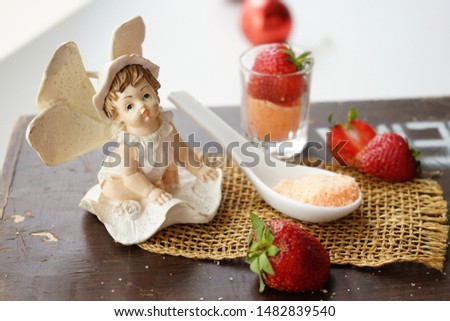 Cute little fairy sitting beside red strawberry fruit