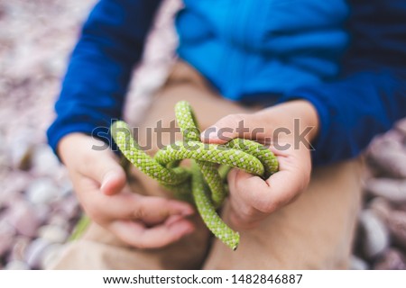 A child learns to knit a knot from a rope. A little boy is trying to tie a knot. Scout training. Children's hands and safety rope. Royalty-Free Stock Photo #1482846887