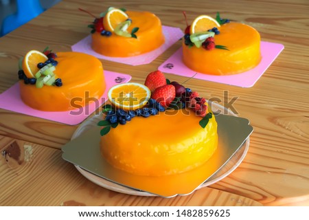 Orange cakes (sponge cake) put on wooden tray decorate the cake with fresh fruit,mix berry,Blueberry,Strawberry,Mulberry and Orange slices and green leaves.