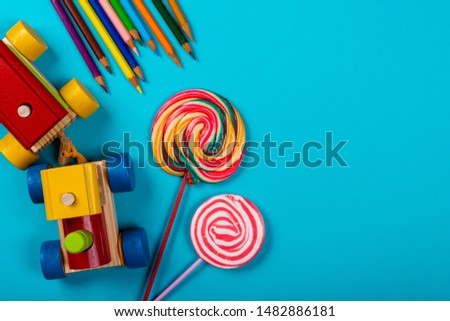 Children's Day. Wooden train, lollipop and colorful color pencils on blue background. Copy space.
