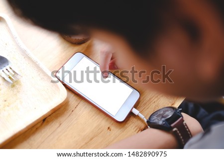Close up of man using blank cell phone and credit card sending massages shopping online or reporting lost card, fraudulent transaction within the coffee shop.