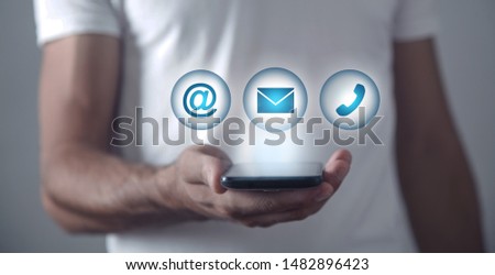 Man holding smartphone with contact symbols.