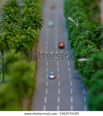 The view of a highway with green trees and cars in miniature size of modelling. 
