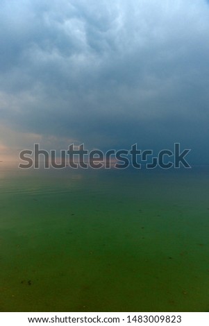 Sea, green water and horizon with clouds in the evening