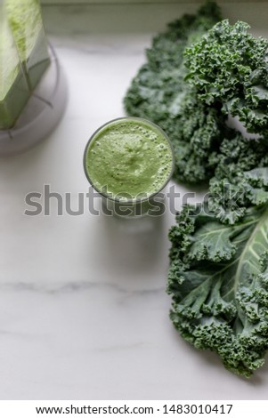 Green smoothies with kale, banana and apple on marble background with copy space