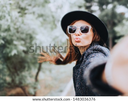 Self portrait of cheerful cute nice beautiful charming girlfriend toothily smiling.Portrait of cheerful young woman with autumn leafs in front of foliage making selfie