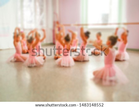 Blurred picture of group of litle ballerinas in pink dresses on a ballet lesson.
