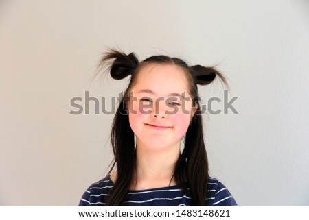 Cute smiling down syndrome girl on the grey background