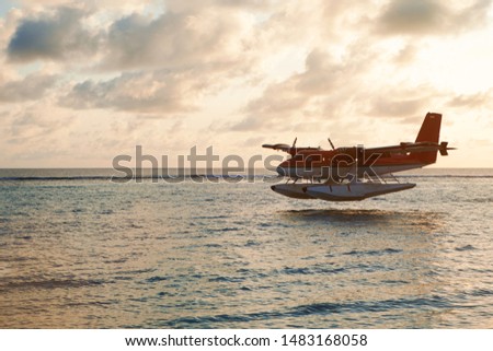 Summer sunset with seaplane. Landing seaplane on the dawn seashore. Calm scenery on evening sea.