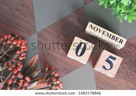 November 5. Date of November month. Number Cube with a flower leaves and bush on Diamond wood table for the background