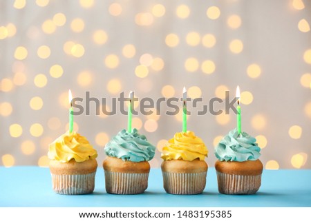Tasty Birthday cupcakes on table against defocused lights