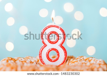 Candle number eight on a blue background. Cake happy birthday candles. Bokeh. Royalty-Free Stock Photo #1483230302
