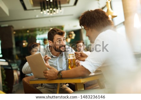 Men are sitting at table in modern cafe. Talk about work