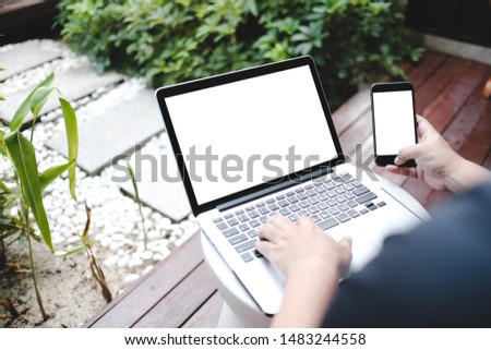 Close up of man using blank cell phone,laptop and credit card sending massages shopping online or reporting lost card, fraudulent transaction within the coffee shop.
