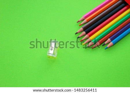 Drawings with colored pencils on a green background a sharpener